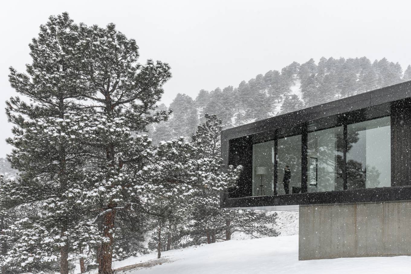 The homes facade is sheathed in a glossy metal to reflect the landscape while staying durable and fire resistant, countering the harsh mountain environment